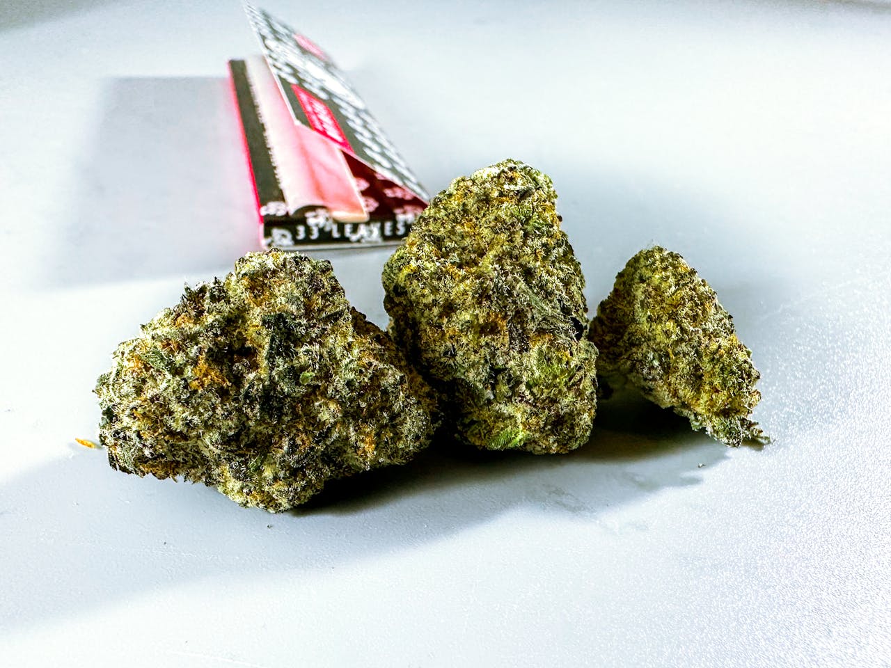 Detailed close-up of cannabis buds displayed on a white background, highlighting texture and color.